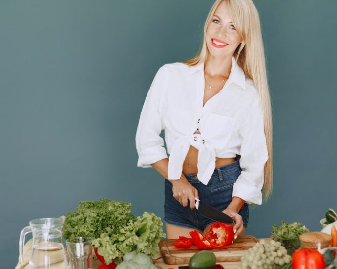 A smiling blonde woman chops vegetables, promoting healthy eating and lifestyle.